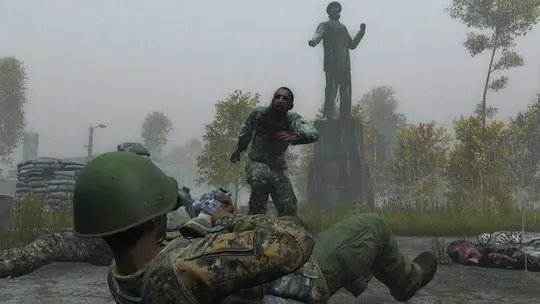A DayZ player in military gear and a green helmet lies prone in the grass, aiming a weapon toward an enemy survivor standing near a stone statue.
