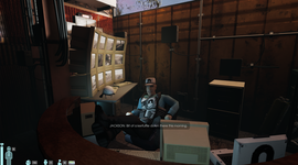 A person in a security room monitors multiple screens, wearing a cap and uniform. Text on screen reads, "JACKSON: Bit of a kerfuffle down there this morning."