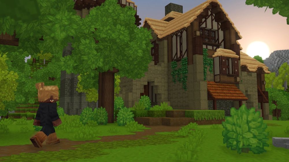 Voxel-style character walks toward a timber-framed stone house with thatched roofs at sunset, surrounded by lush blocky trees.