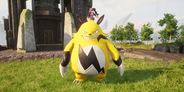 A large, yellow creature with black markings stands on grass, with a small figure on its head. A futuristic building and trees are in the background.