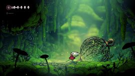 A small character with a red cloak stands in a lush, green, mystical forest near a large, ornate, spherical cage.