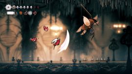 A character battles a flying creature with a lance in a dimly lit, cavernous setting, surrounded by spikes and glowing symbols.