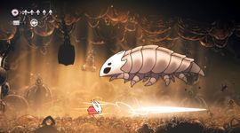 A small character in a red cape battles a large, armored insect in a dimly lit cavern, with glowing eyes and hanging chains in the background.