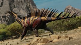 A Miragaia dinosaur with prominent neck spikes and a patterned brown and yellow hide walking through a sandy desert biome in Path of Titans.