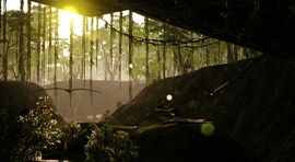 A cinematic view from inside a dark, rocky cave looking out into a lush, sun-drenched jungle with hanging vines and bright lens flare.