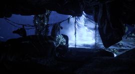 A view from inside a dark underwater cavern in Beasts of Bermuda, looking out at vibrant blue water illuminated by rays of light filtering through the surface.