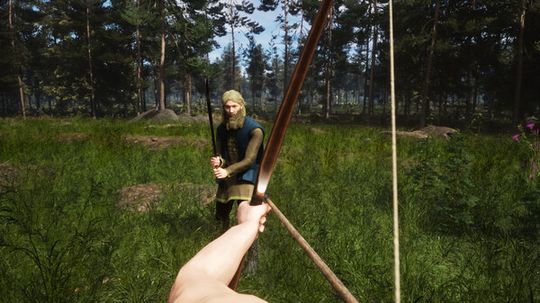 First-person view of a bow aimed at a person standing in a lush forest, surrounded by tall trees and greenery under a clear sky.