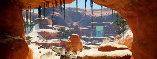 A view from the interior of a rocky orange cave looking out across a sun-drenched desert canyon toward ancient stone ruins and distant mesas.